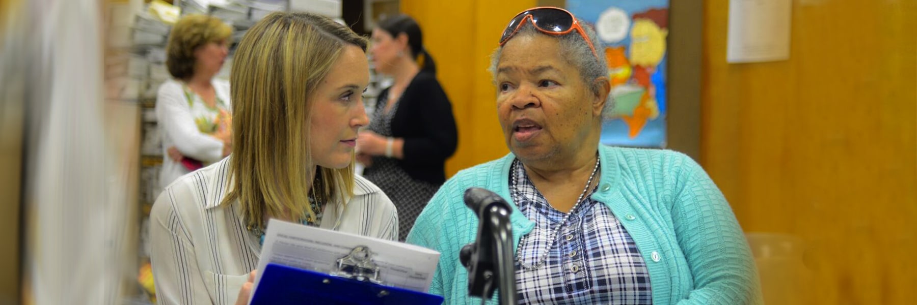 Two women talk at microphone at community engaged event.