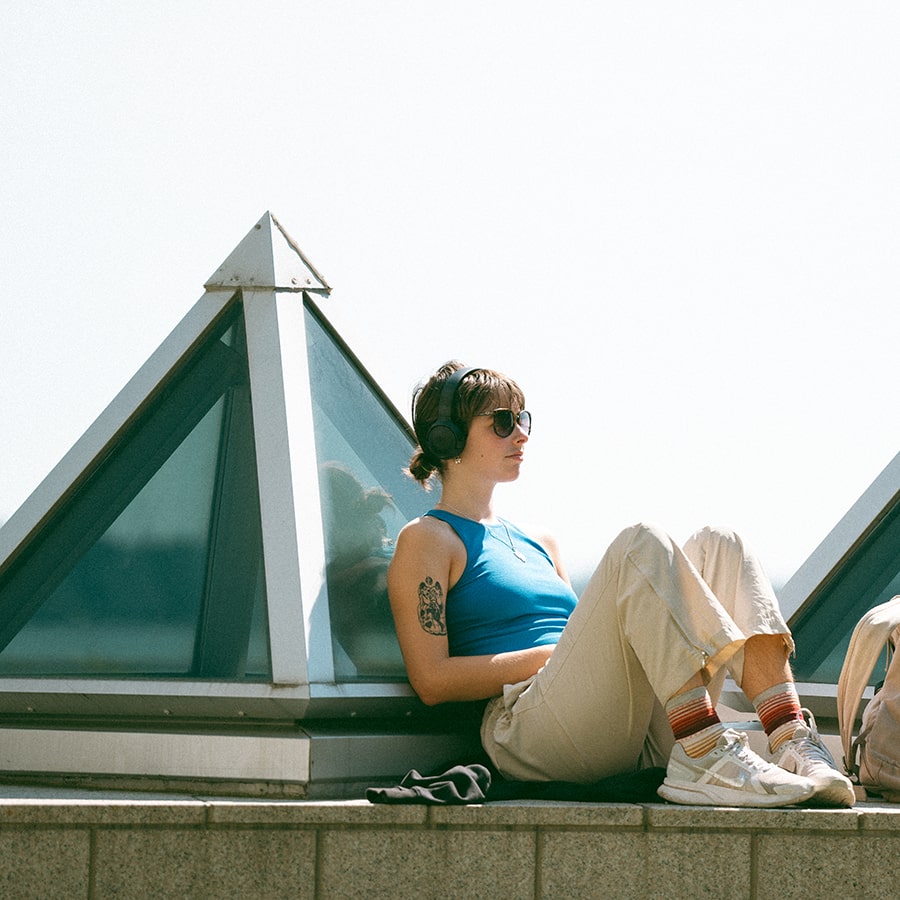 student sits relaxing with headphones on the pyramids outside Campus Center