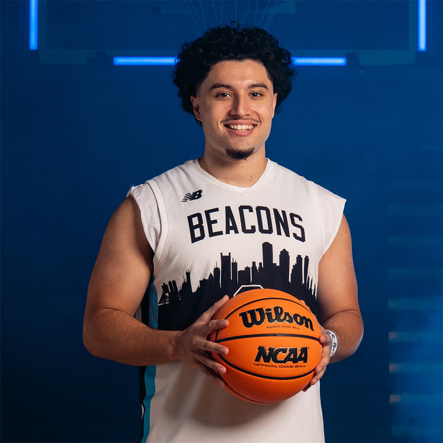 Student, Hector, smiling and holding a basketball.