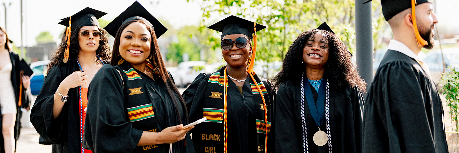 4 students in caps, gowns, stoles with African colors