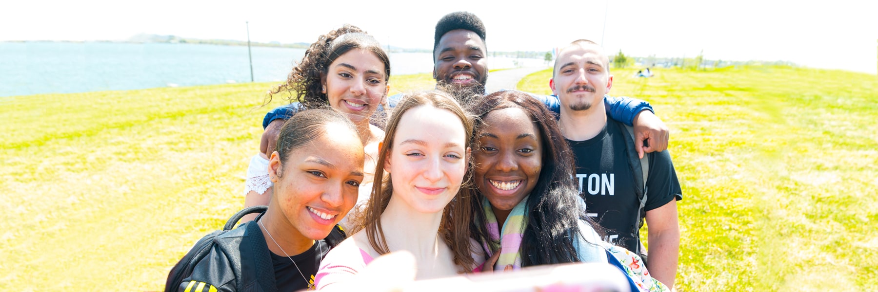 students on campus lawn taking selfie